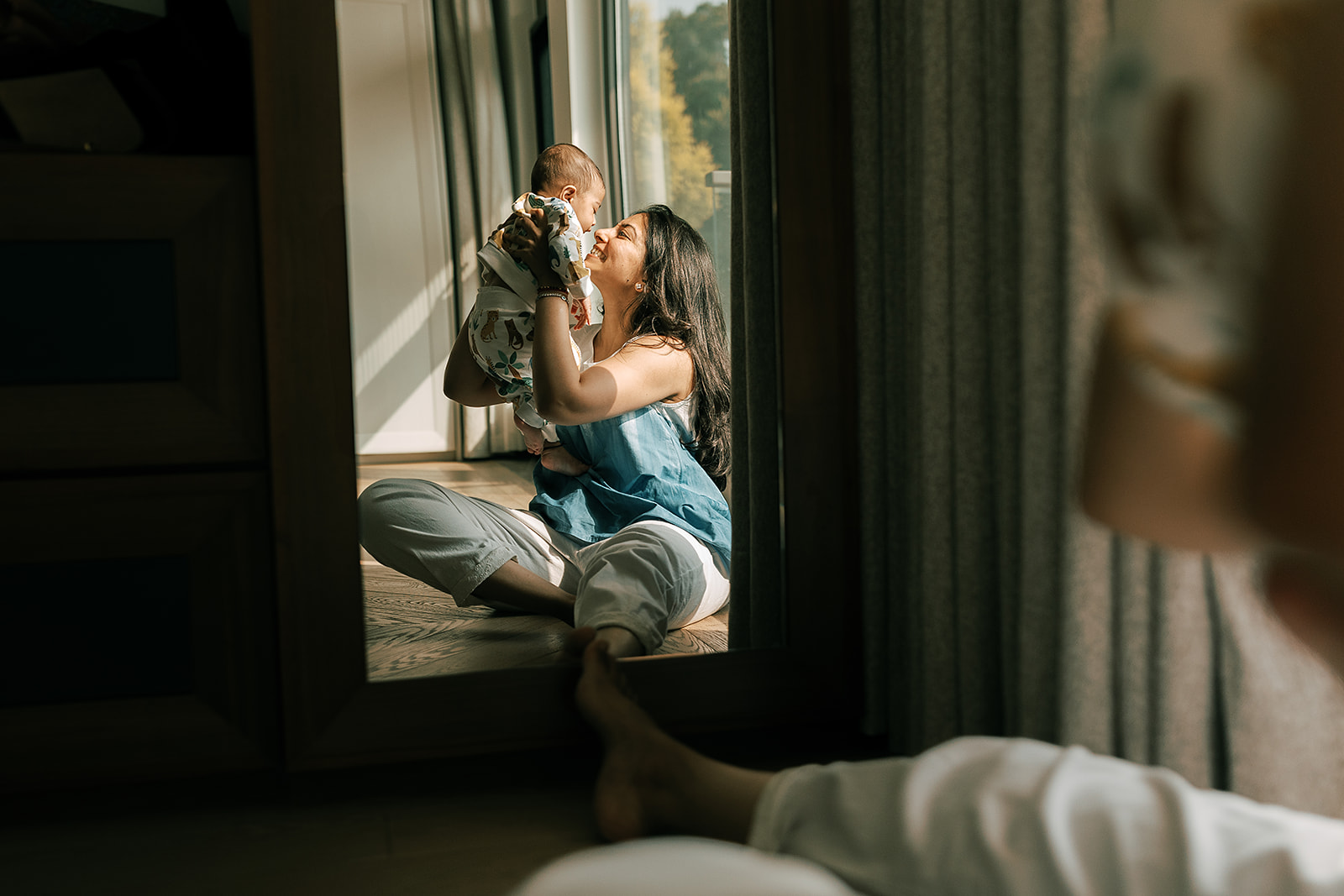 Mother playing with baby on the floor of a living room.