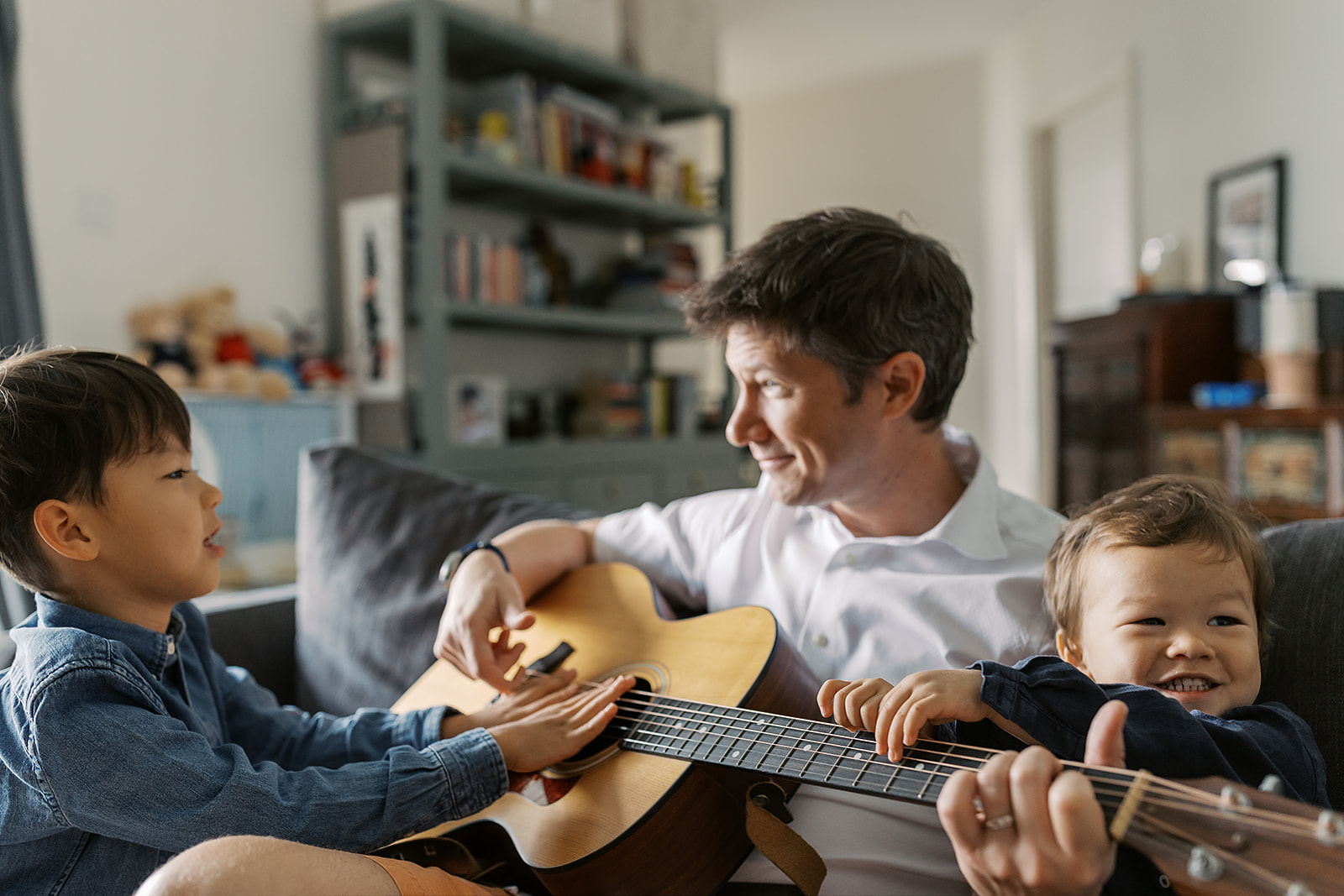 Family laughing together during a game in the sofa.