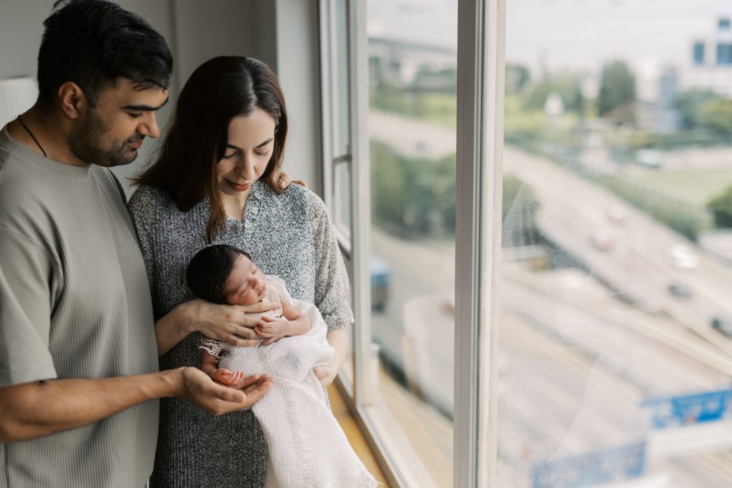 Hong Kong in-home newborn photographer captures a parent holding their sleeping newborn in natural window light